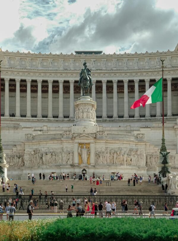 Home Vittorio Emanuele II Monument in Rome with Italian flags and tourists visiting.